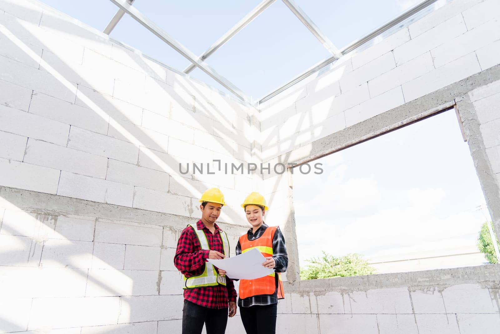Architect and client discussing the plan with blueprint of the building at construction site. Asian engineer foreman worker man and woman working talking and checking on draw paper to checking project