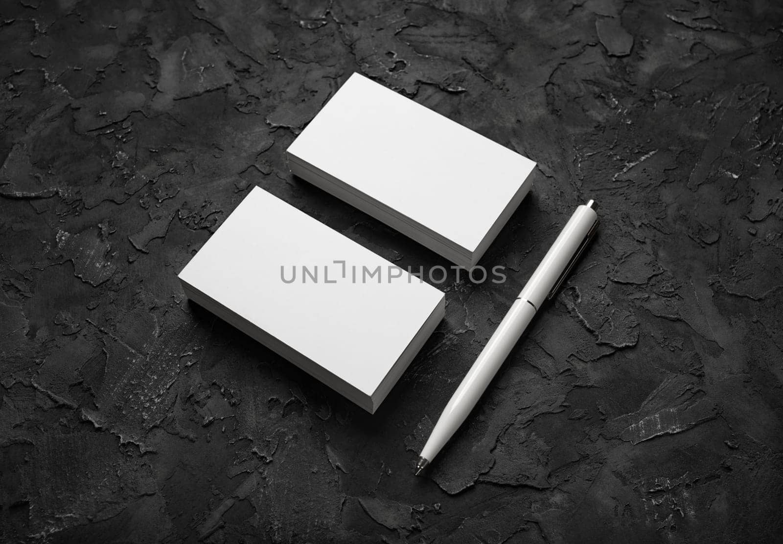 Blank business cards and pen on black stone background. Mockup for branding identity. Template for graphic designers portfolios.