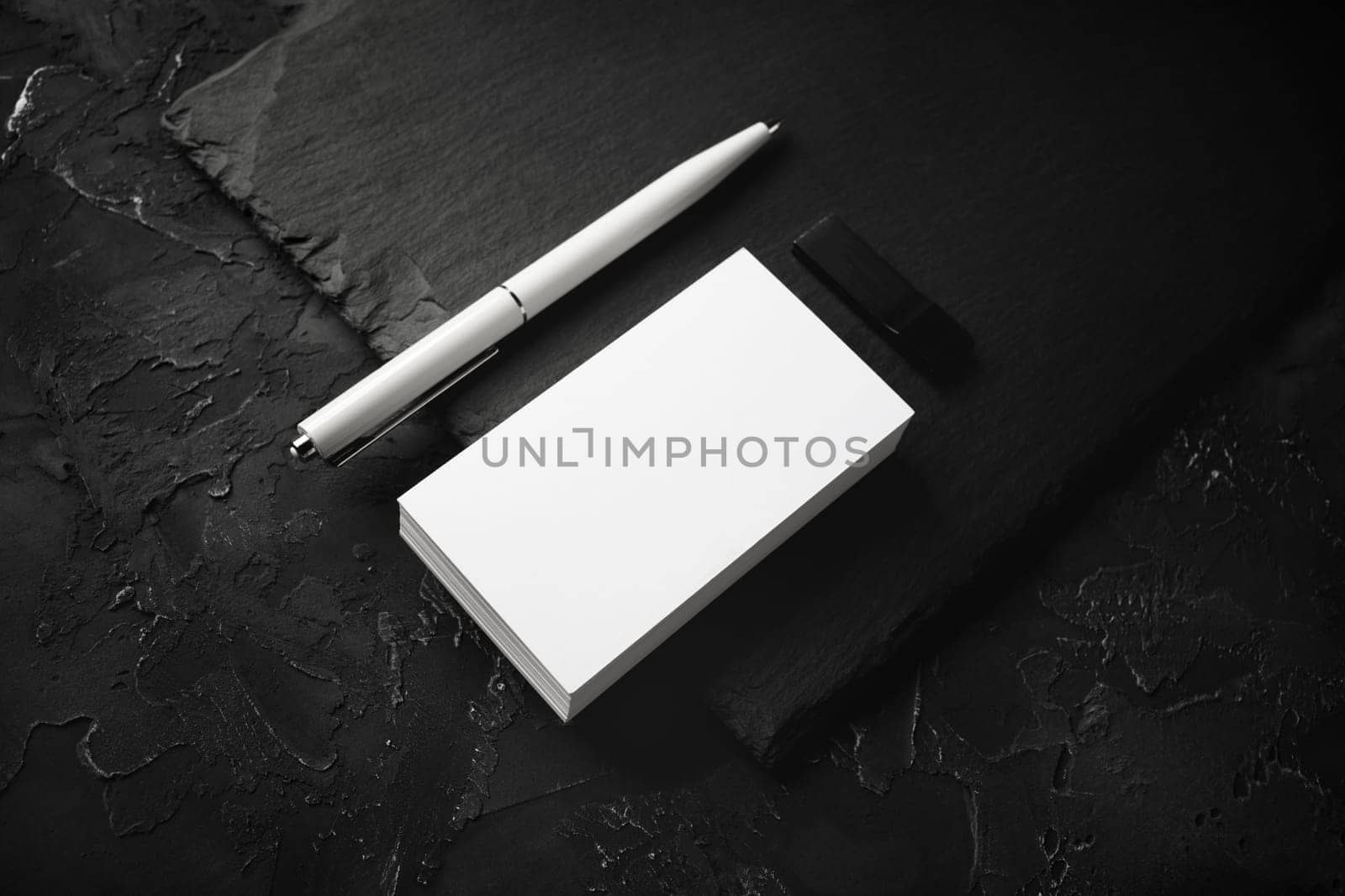 Photo of blank business cards, pen, usb flash drive and slate plate on black stone background. Branding mock up.