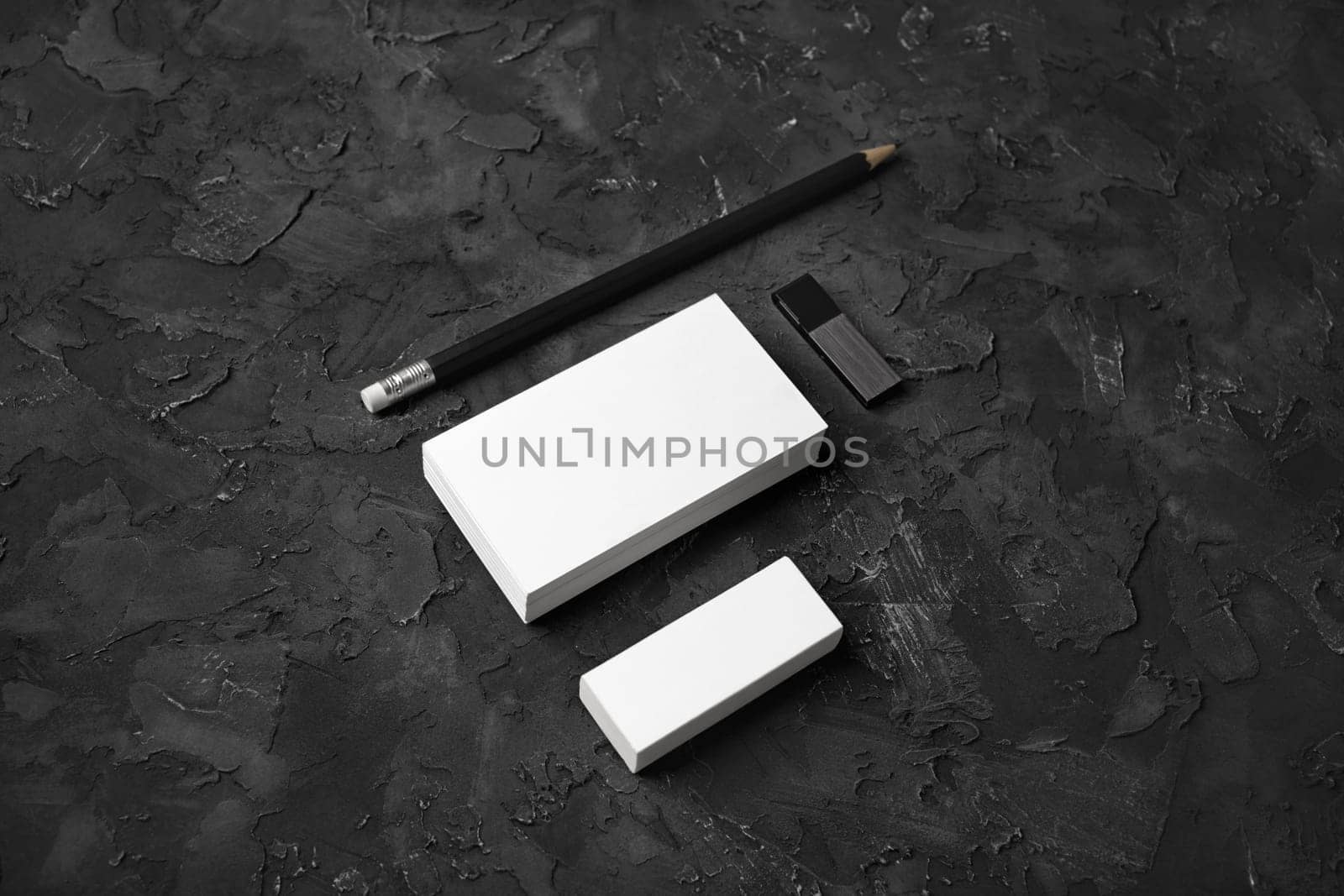 Blank business cards, pencil, eraser and usb flash drive on black stone background. Blank stationery set.