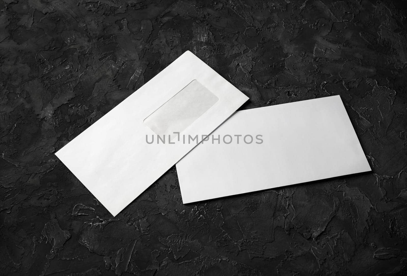 Two blank envelopes on black stone background. Back and front. Template for branding identity.