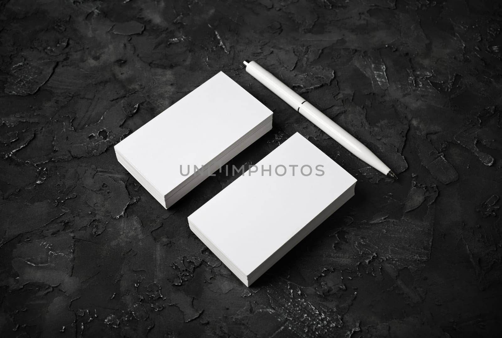Photo of blank business cards and pen on black stone background. Template for ID.