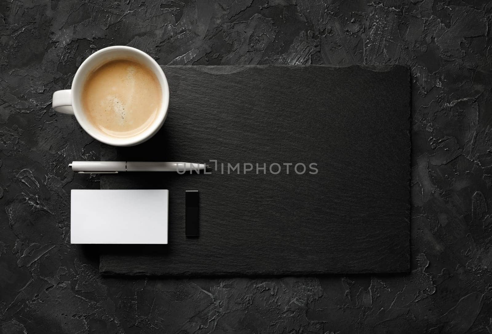 Blank business card, coffee cup, pen, usb flash drive and slate plate on black stone background. Template for placing your design. Flat lay.