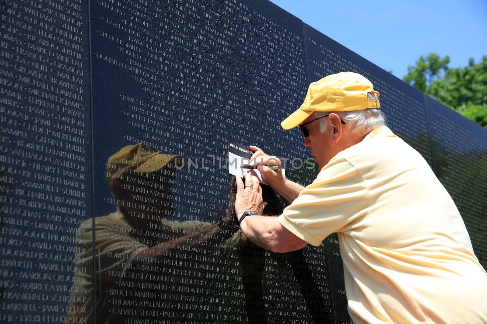 Volunteer take a rubbing of a Name at the Vietnam War Memorial on the Mall in Washington DC. USA