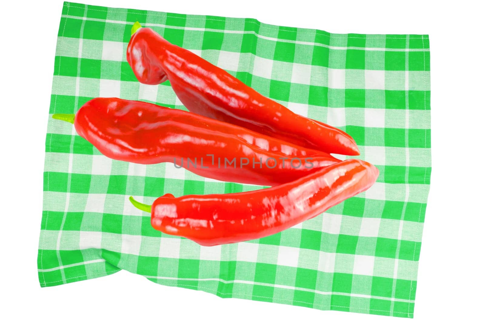 Vegetables and fruits. Top view of three fresh red peppers on a green checkered tablecloth or napkin isolated on a white background. Health concept.