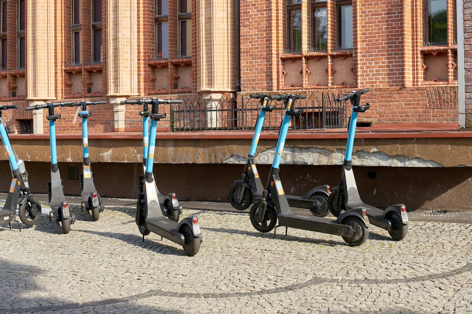 parked e-scooters of the company OKAI in front of the town hall of the city of Kolobrzeg in Poland are ready to be borrowed