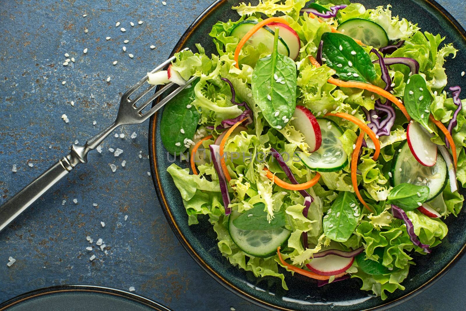 Green lettuce salad meal with fresh mixed vegetables on blue table background