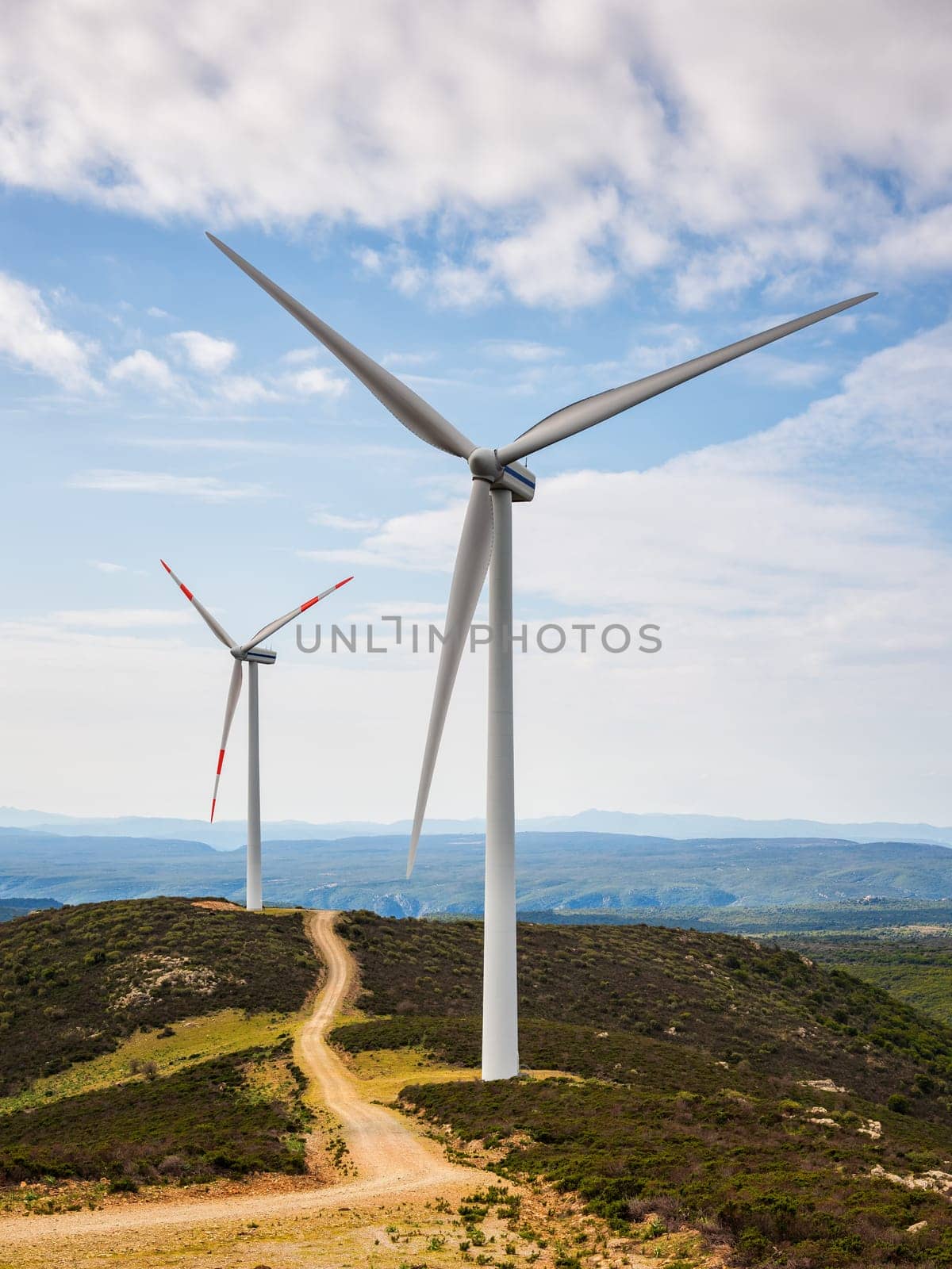 Wind turbines on a beautiful blue sky with clouds in a mountain wind farm in Sardinia. Renewable energy concept, green energy generation. Energy industry.