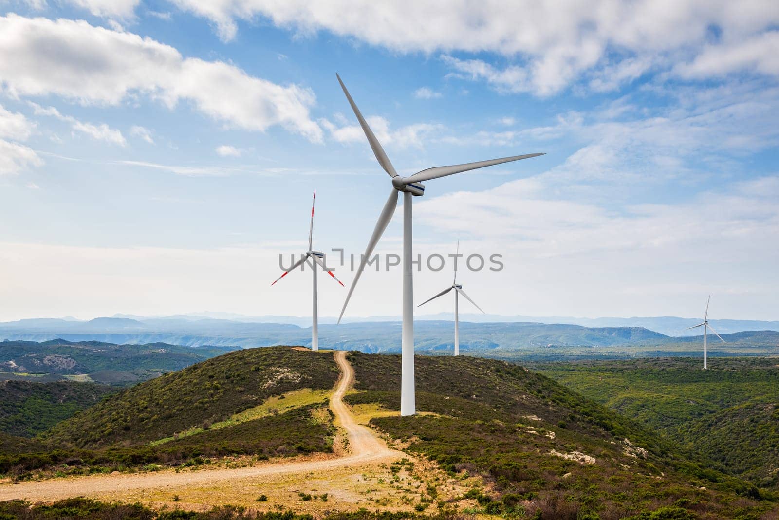 Wind turbines on a beautiful blue sky with clouds in a mountain wind farm in Sardinia. Renewable energy concept, green energy generation. Energy industry.