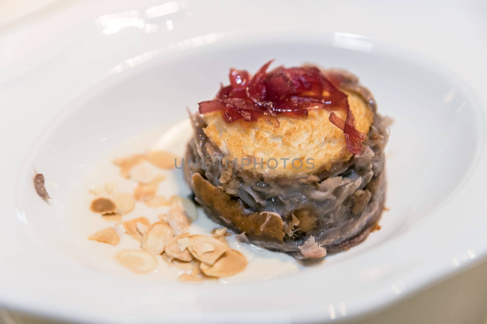 Quiche, pie with onions and almonds, served on porcelain white plate.