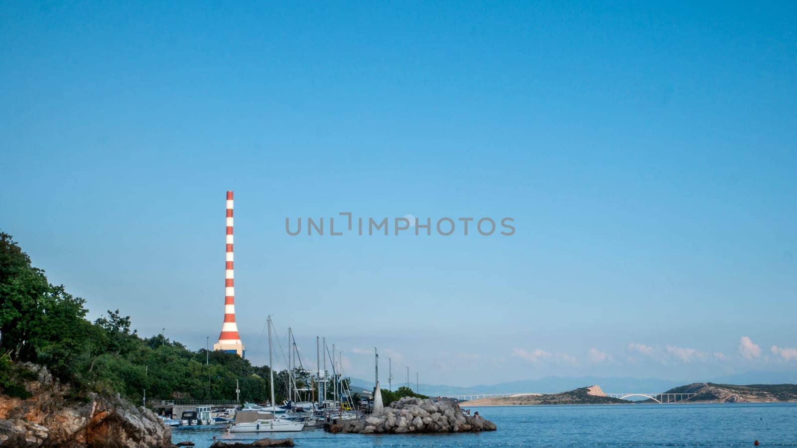 View of boats and a large industrial chimney from the beach in Kostrena, northern Adriatic, Croatia