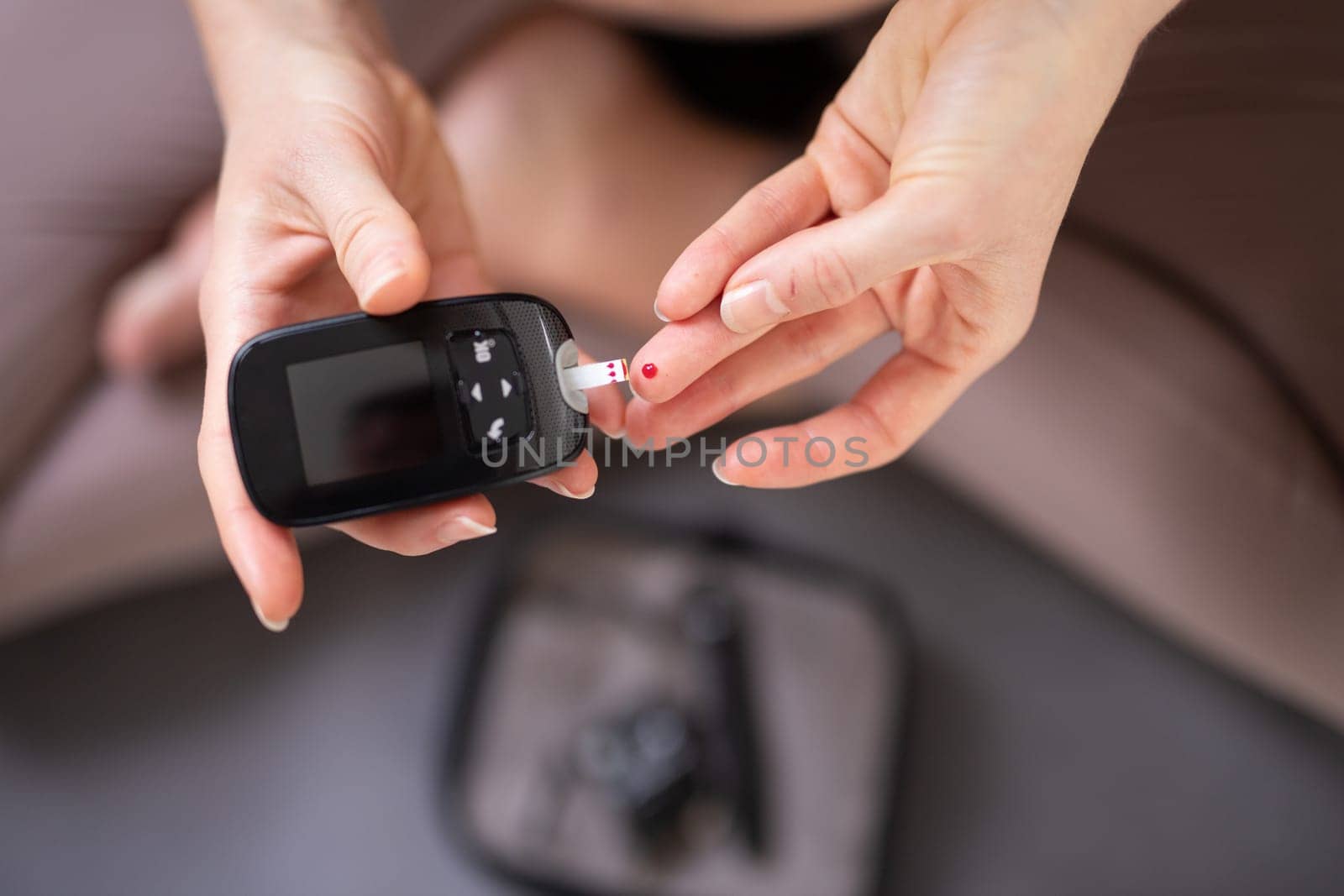 Blood sugar testing at home. Woman checking blood sugar level by glucometer and test stripe at home. Diabetic checking blood sugar levels