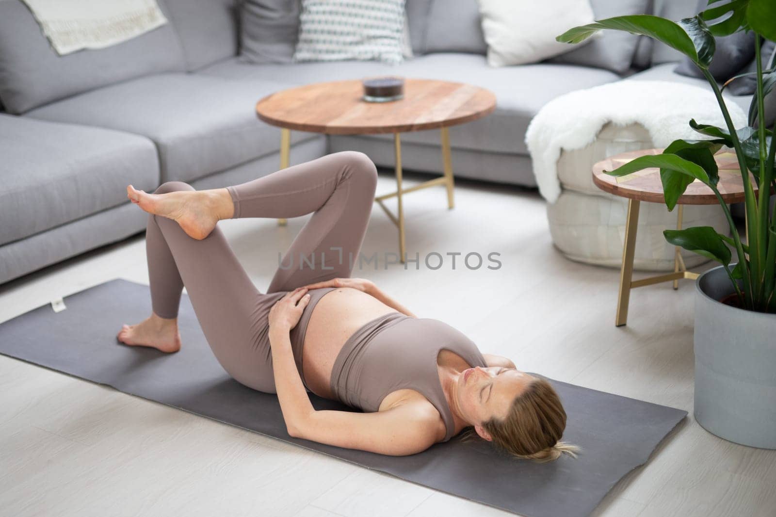 Young beautiful pregnant woman training pilates at home in her living room. Healthy lifestyle and active pregnancy and motherhood concept