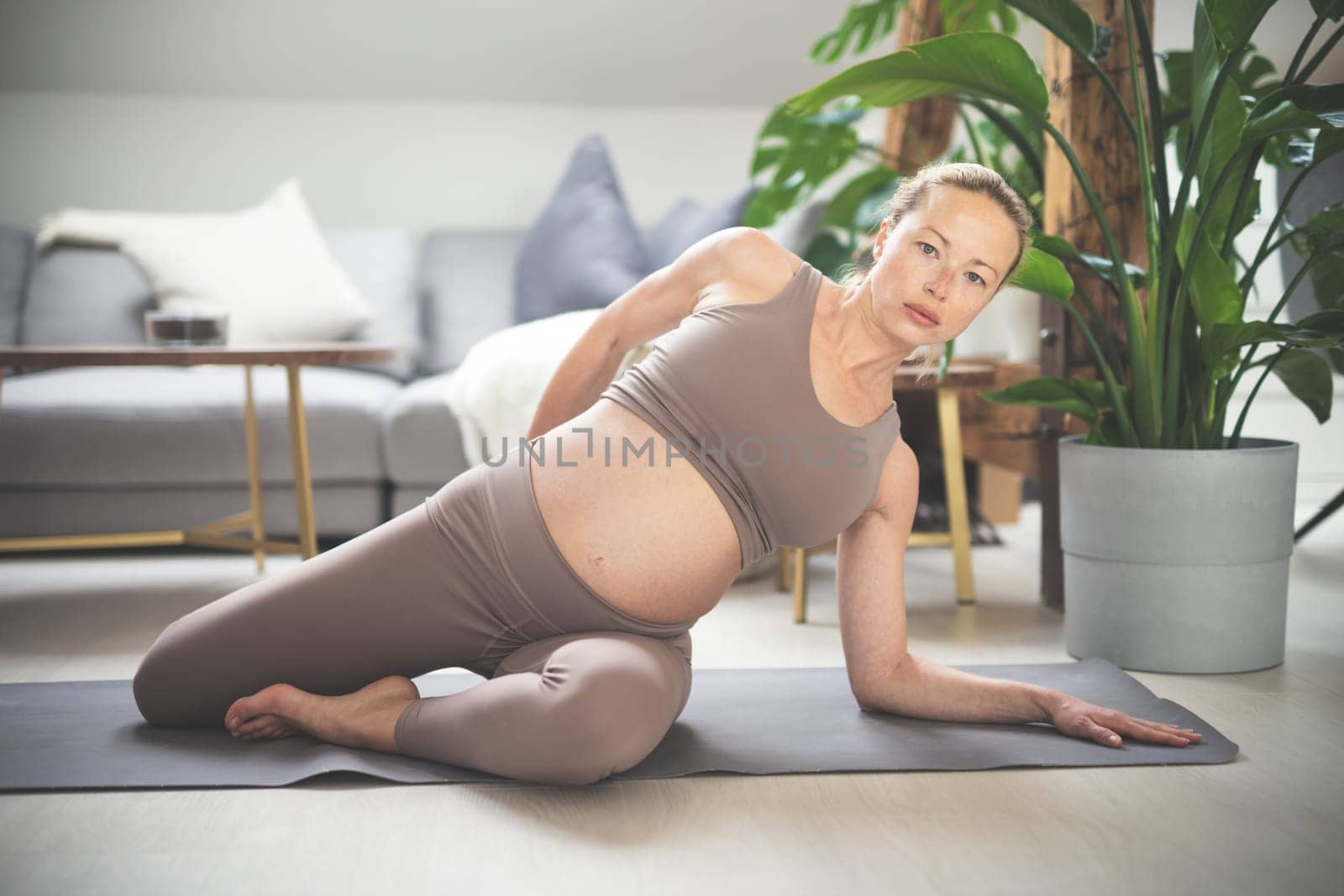 Young beautiful pregnant woman training pilates at home in her living room. Healthy lifestyle and active pregnancy and motherhood concept