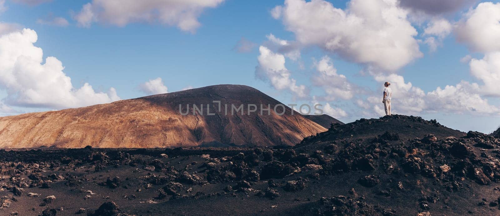 Female tourist enjoying amazing views of volcanic landscape in Timanfaya national park on Lanzarote, Spain. Freedom and travel adventure concept