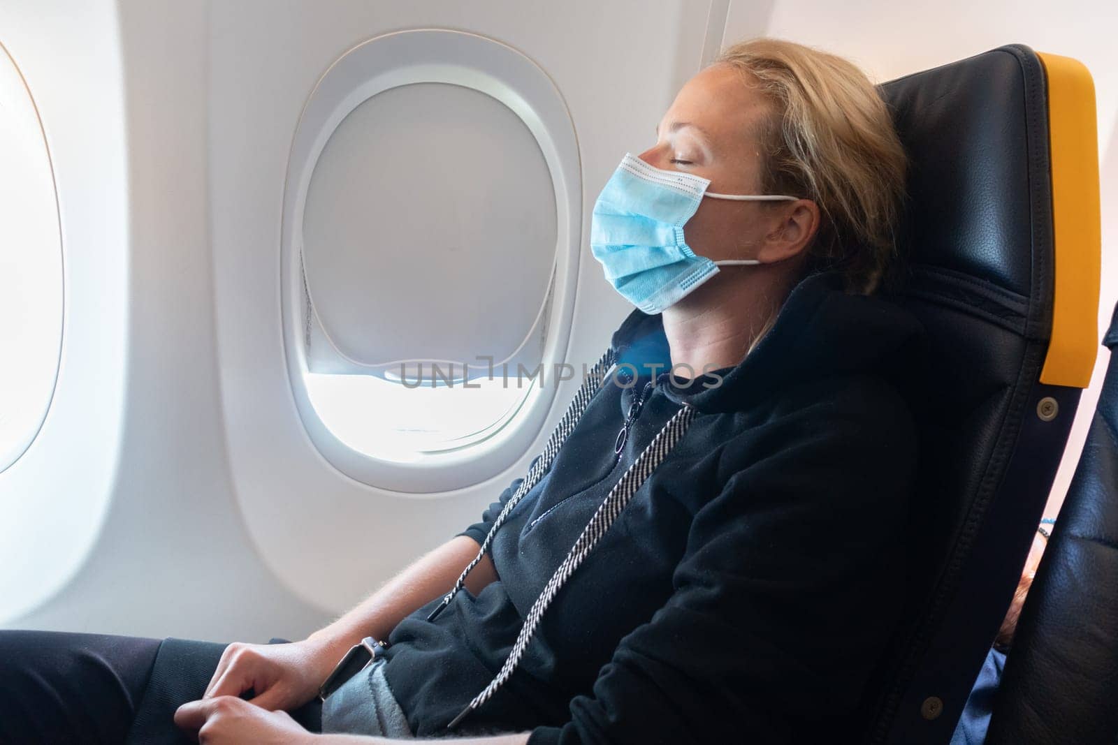 A young woman wearing face mask is traveling on airplane , New normal travel after covid-19 pandemic concept