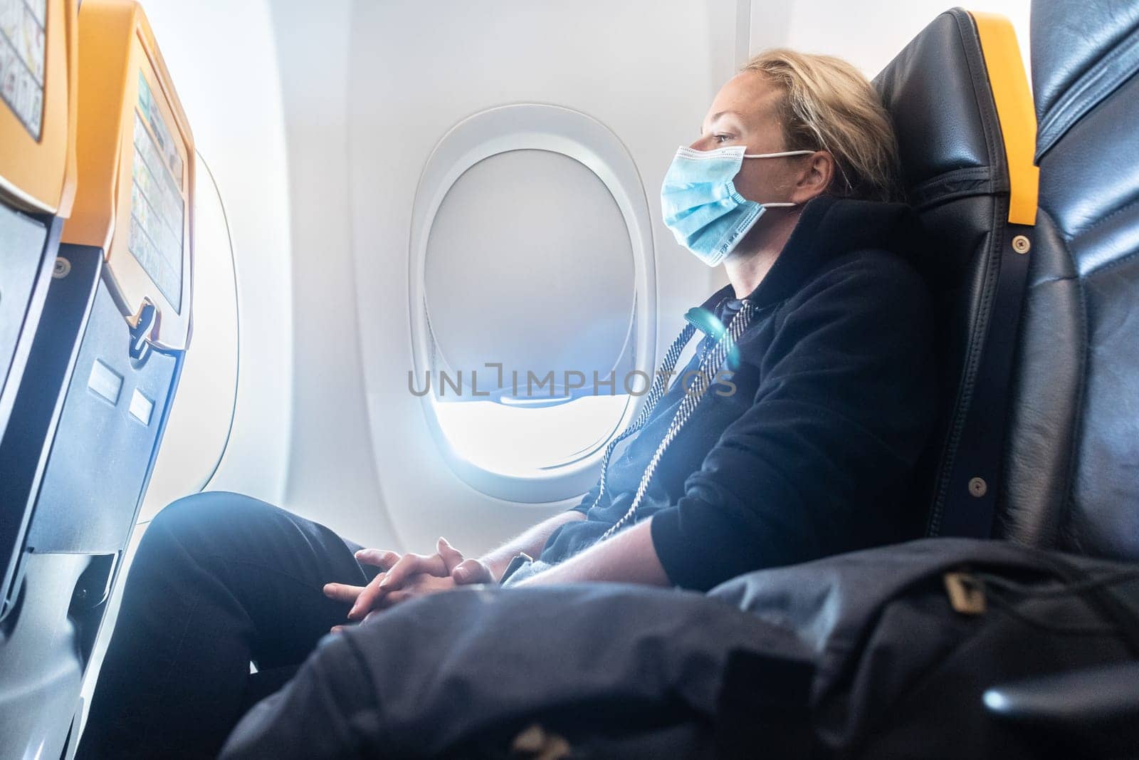A young woman wearing face mask is traveling on airplane , New normal travel after covid-19 pandemic concept