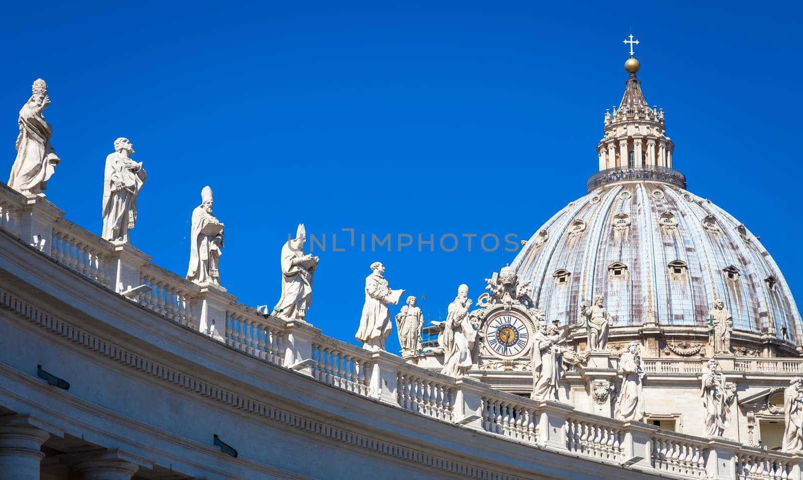 Statues of Catholic Saints. Decorations on Bernini colonnade, Saint Peter Cathedral, with the Cupola in background - Rome, Italy