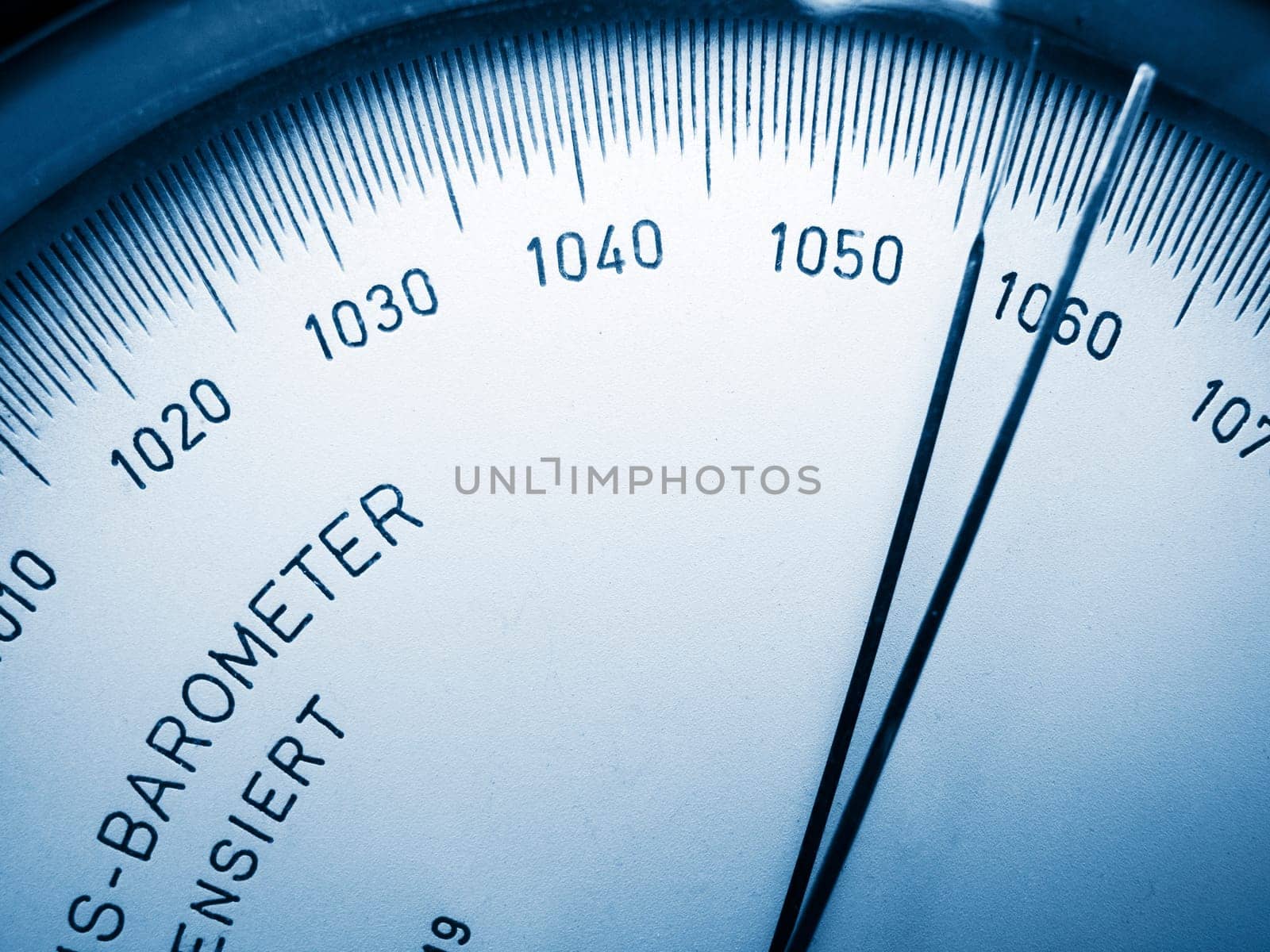 Close-up view of the scale with pointer of an analogue barometer blue toned.