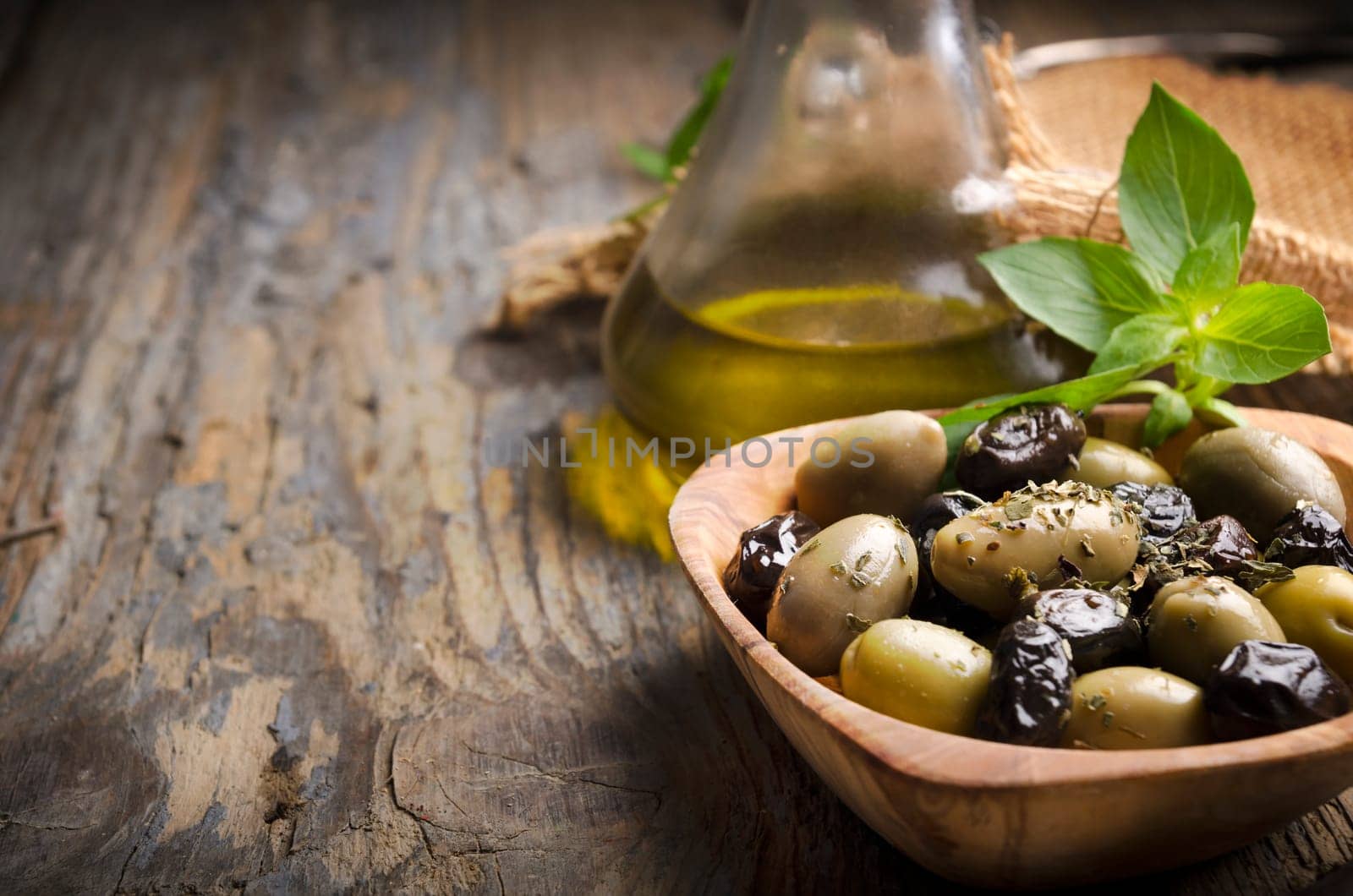 Olives and olive oil on rustic wooden table