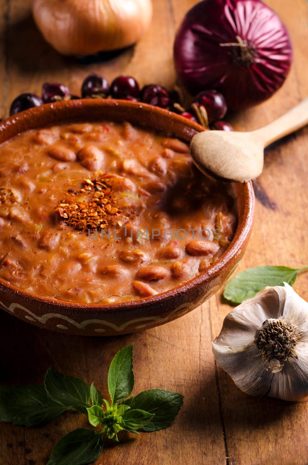 Spicy baked beans in traditional clay bowl