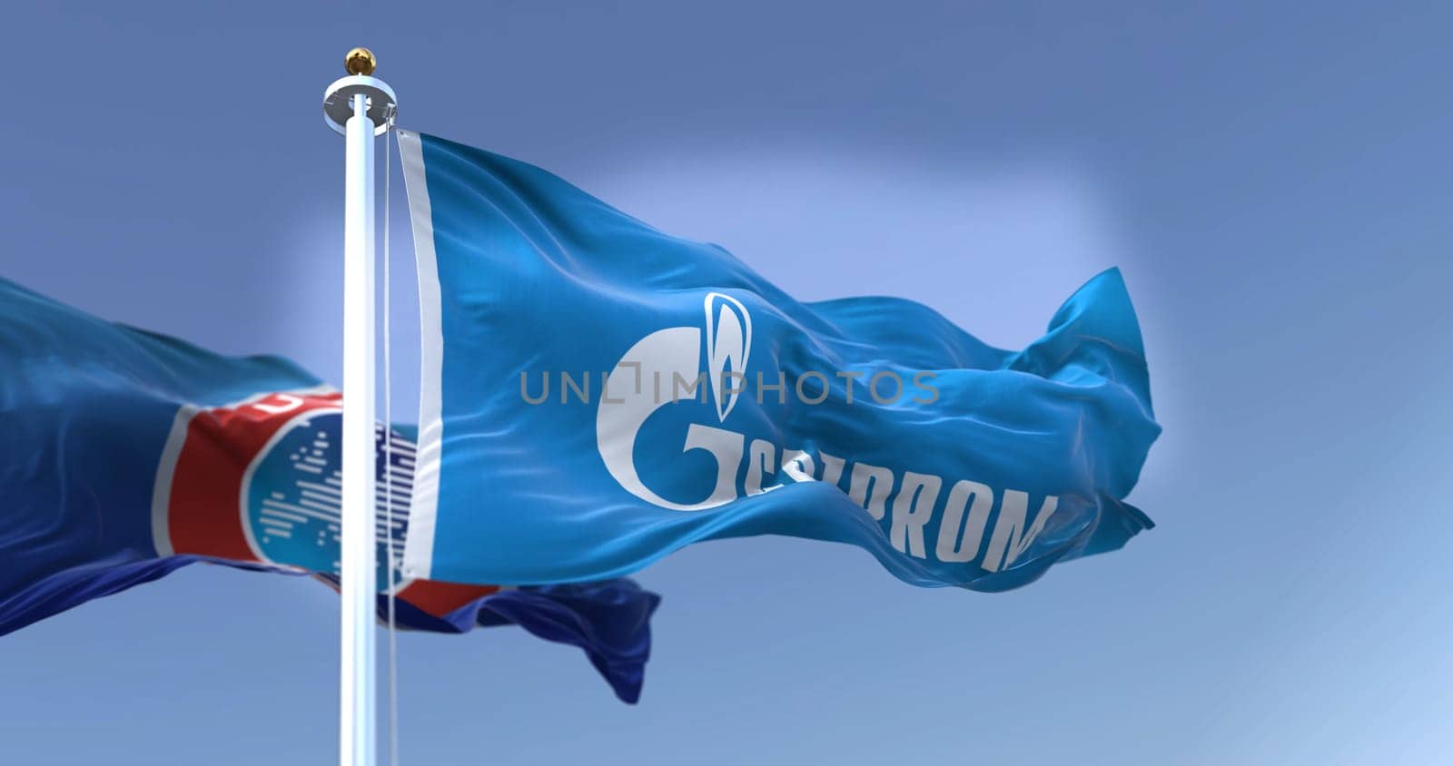 Basel, SWI, February 2022: The flag with the Gazprom logo fluttering in the wind with the UEFA flag blurred in the background. Gazprom is a major sponsor of UEFA