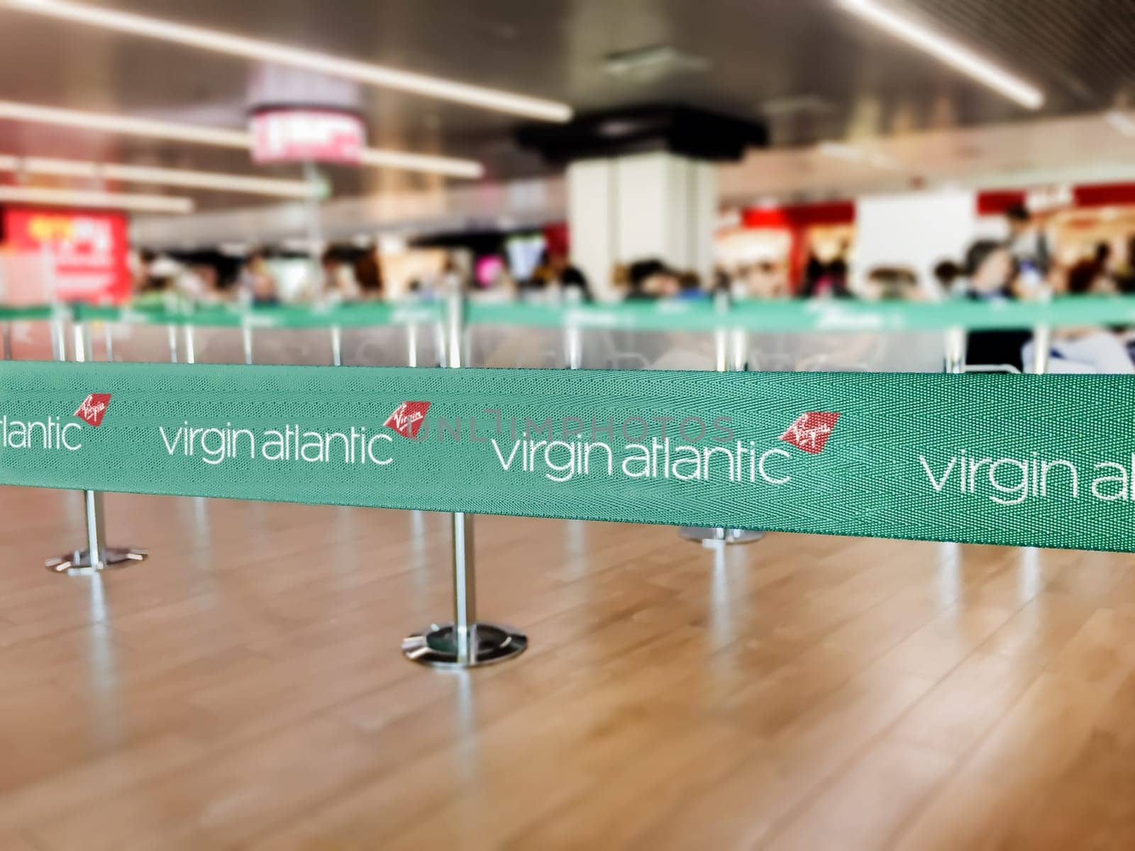 London, UK, July 2019: Green belt barrier with white Virgin Atlantic airlines logo. Virgin Atlantic is a British airline. Travel and airport security