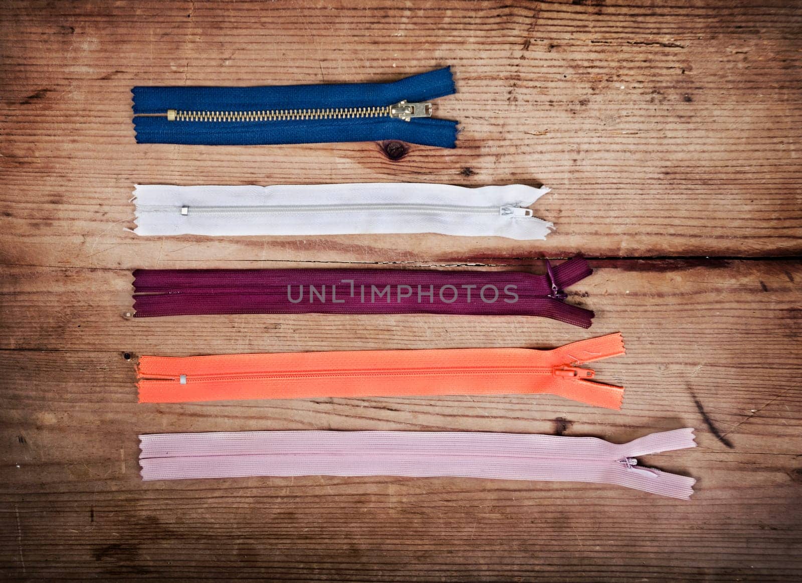 Colorful zippers in different sizes over wooden background