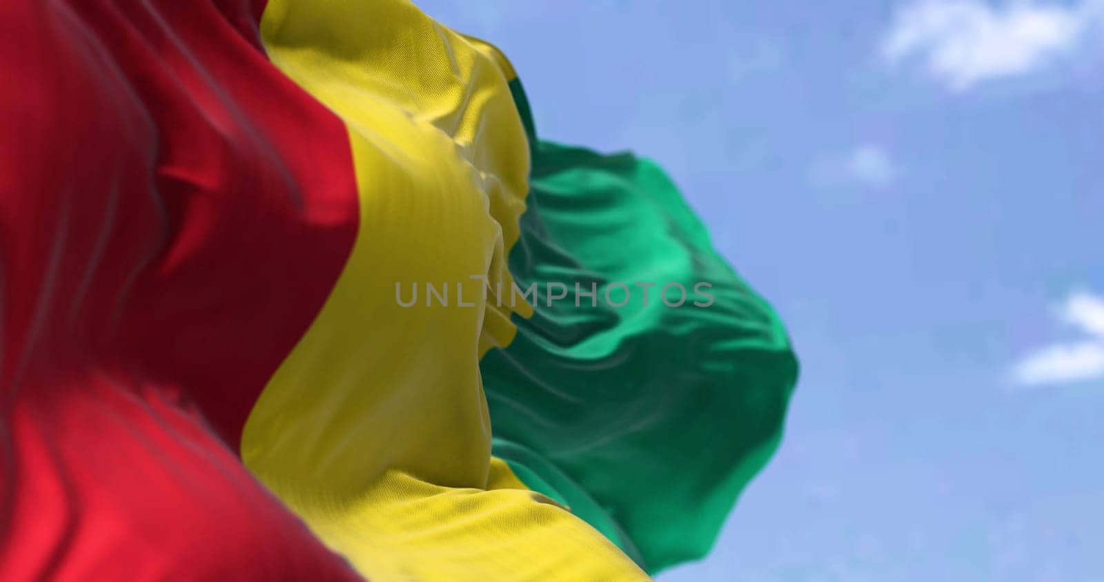 Detail of the national flag of Guinea waving in the wind on a clear day. Guinea is a coastal country in West Africa. Selective focus.