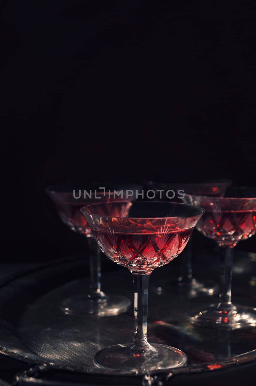 Cherry liqueur in vintage crystal glasses over dark background