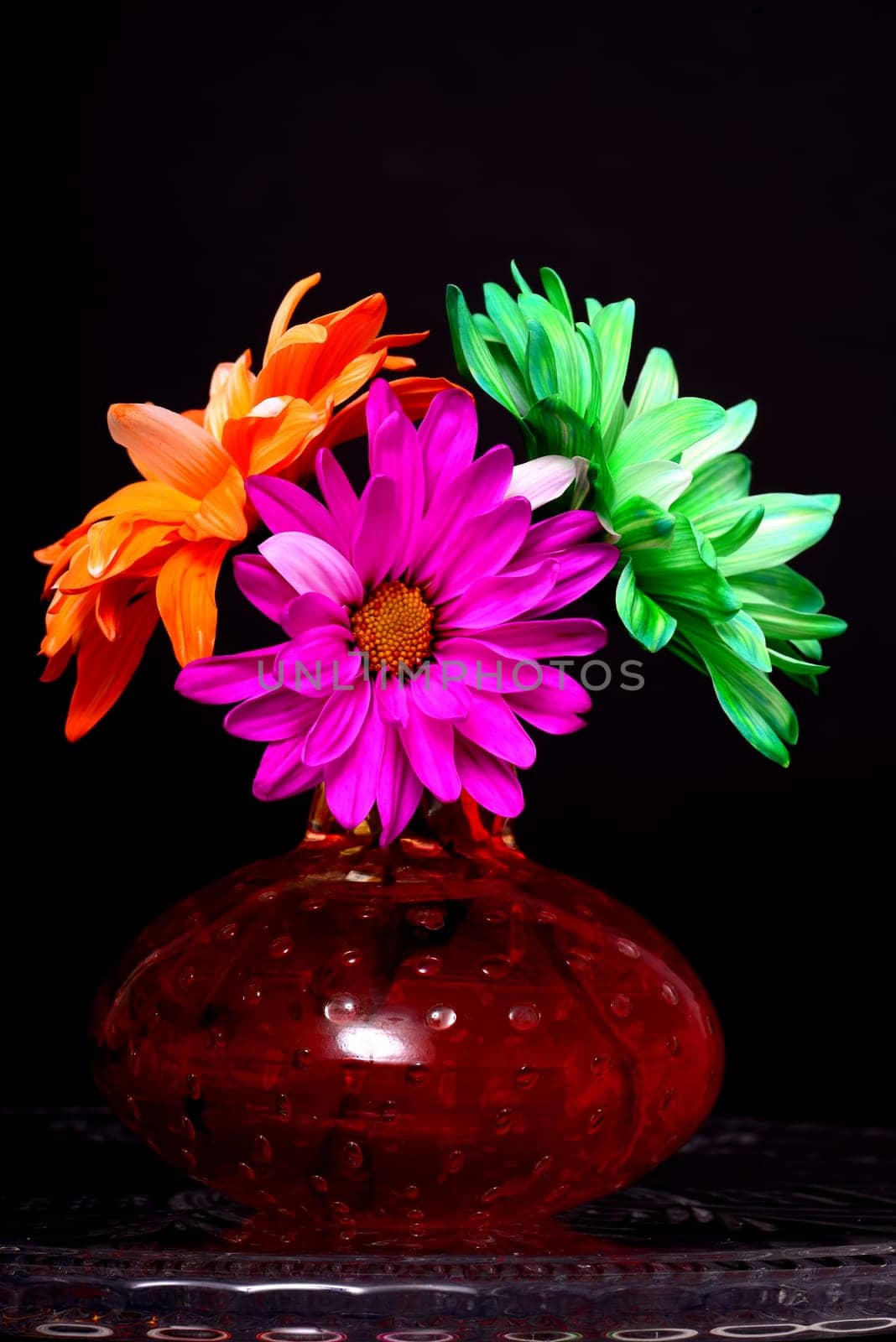 Pink orange and green Floral arrangement in a brown vase isolated over a black background