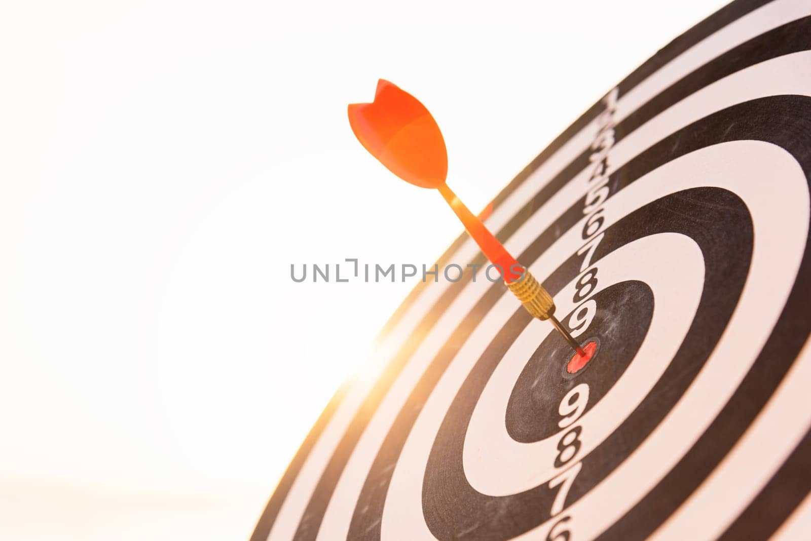 Closeup the dart arrow hit center on Bullseye(bull's-eye) of a dartboard is a target of challenge business, strategy marketing target, objective financial and goal a concept