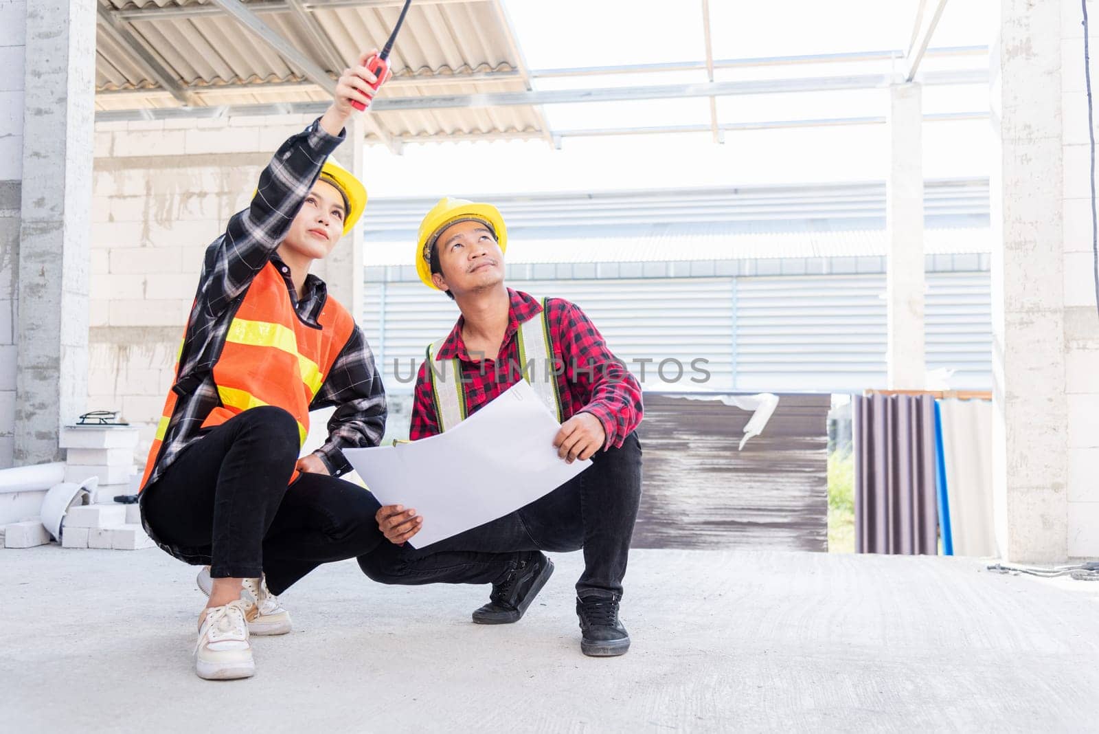 Architect and client discussing help create plan with blueprint of the building at construction site. Asian engineer foreman worker man and woman meeting talking on drawing paper project, team work