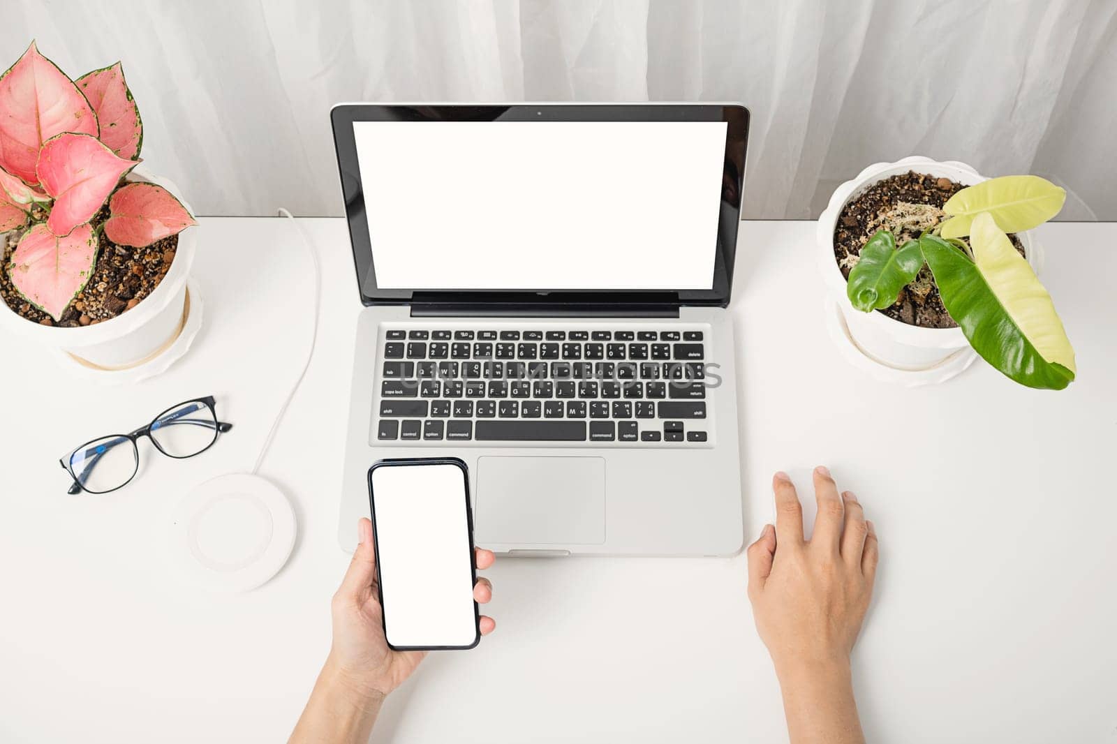 Female sitting workspace using hand holding black smartphone blank screen mock up on a table with laptop computer, female hold mobile phone with notebook at office