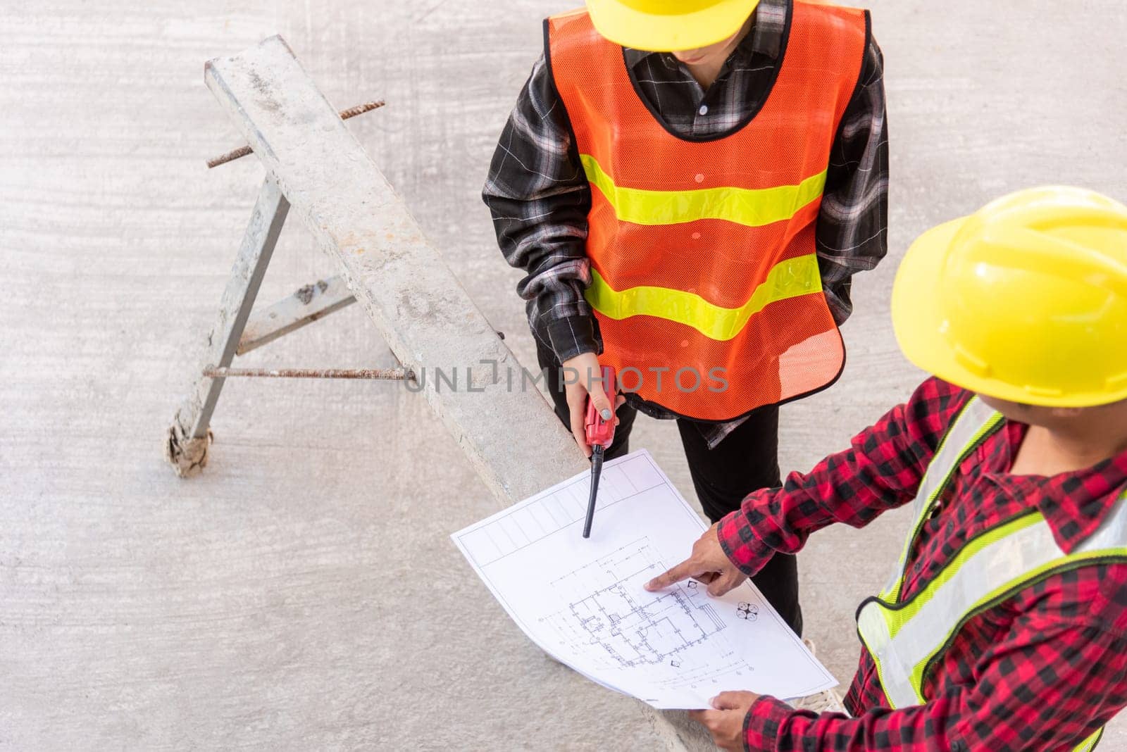 Architect and client discussing help create plan with blueprint of the building at construction site floor. Asian engineer foreman worker man and woman meeting and planning construction work, top view