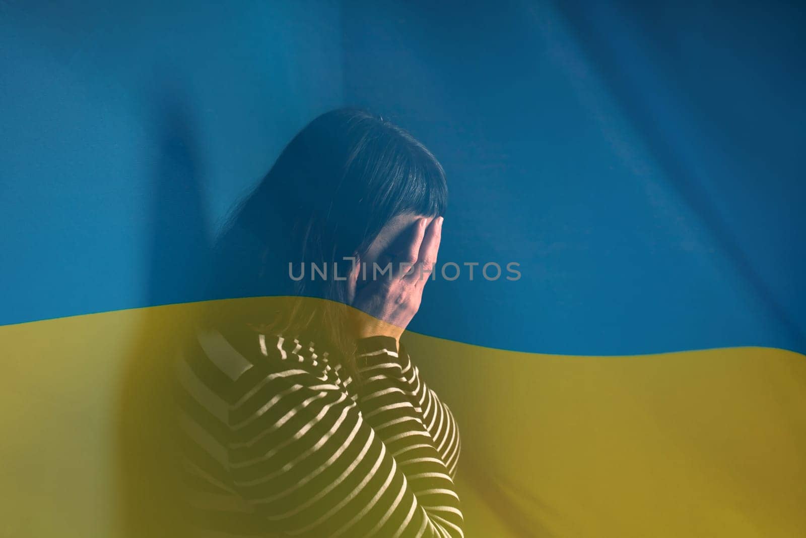 War between Russia and Ukraine. Woman with sad sight over Ukraine flag.