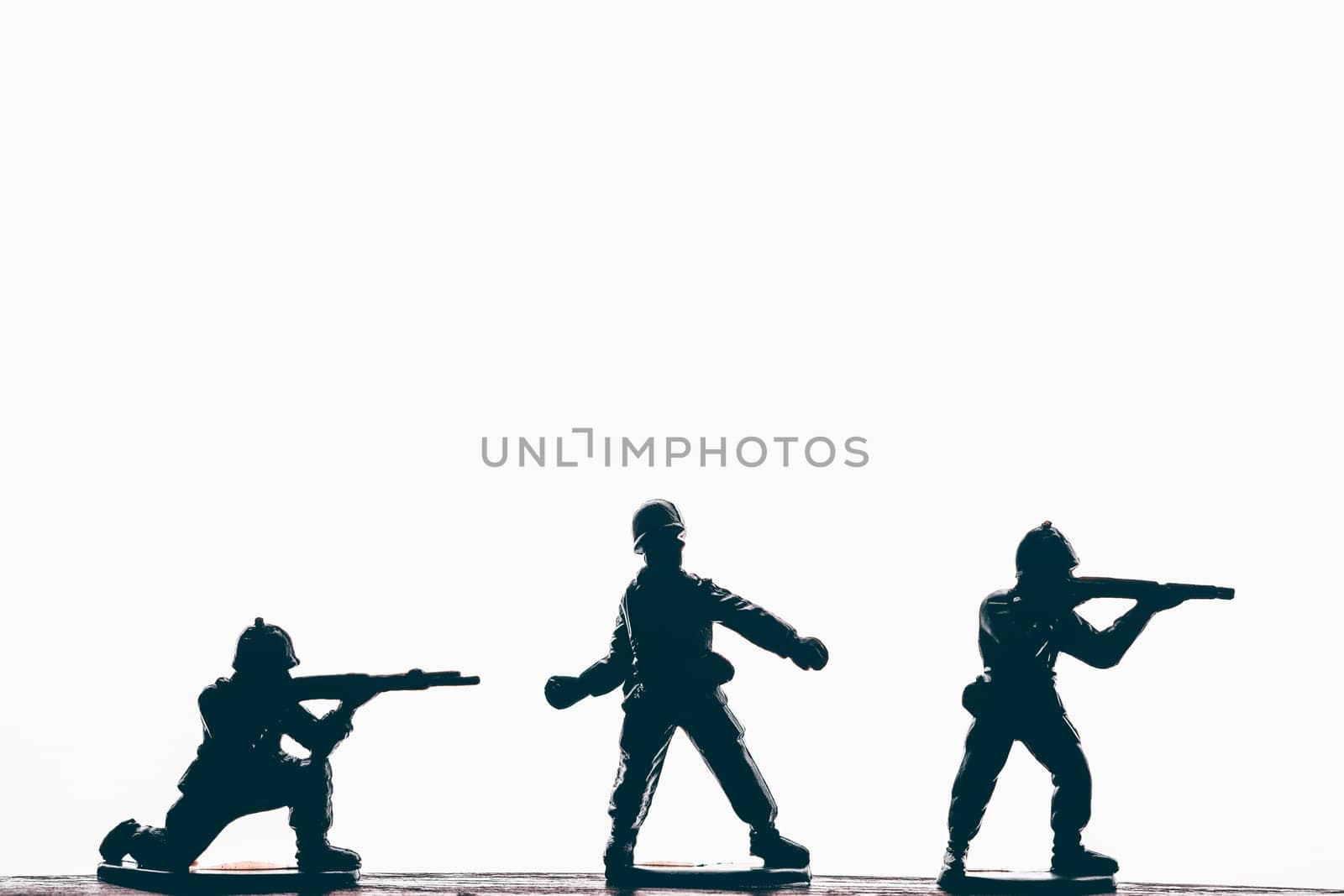 Silhouette of male soldiers wearing army, uniform and helmet. Man holding weapon machine in hands. White studio background.