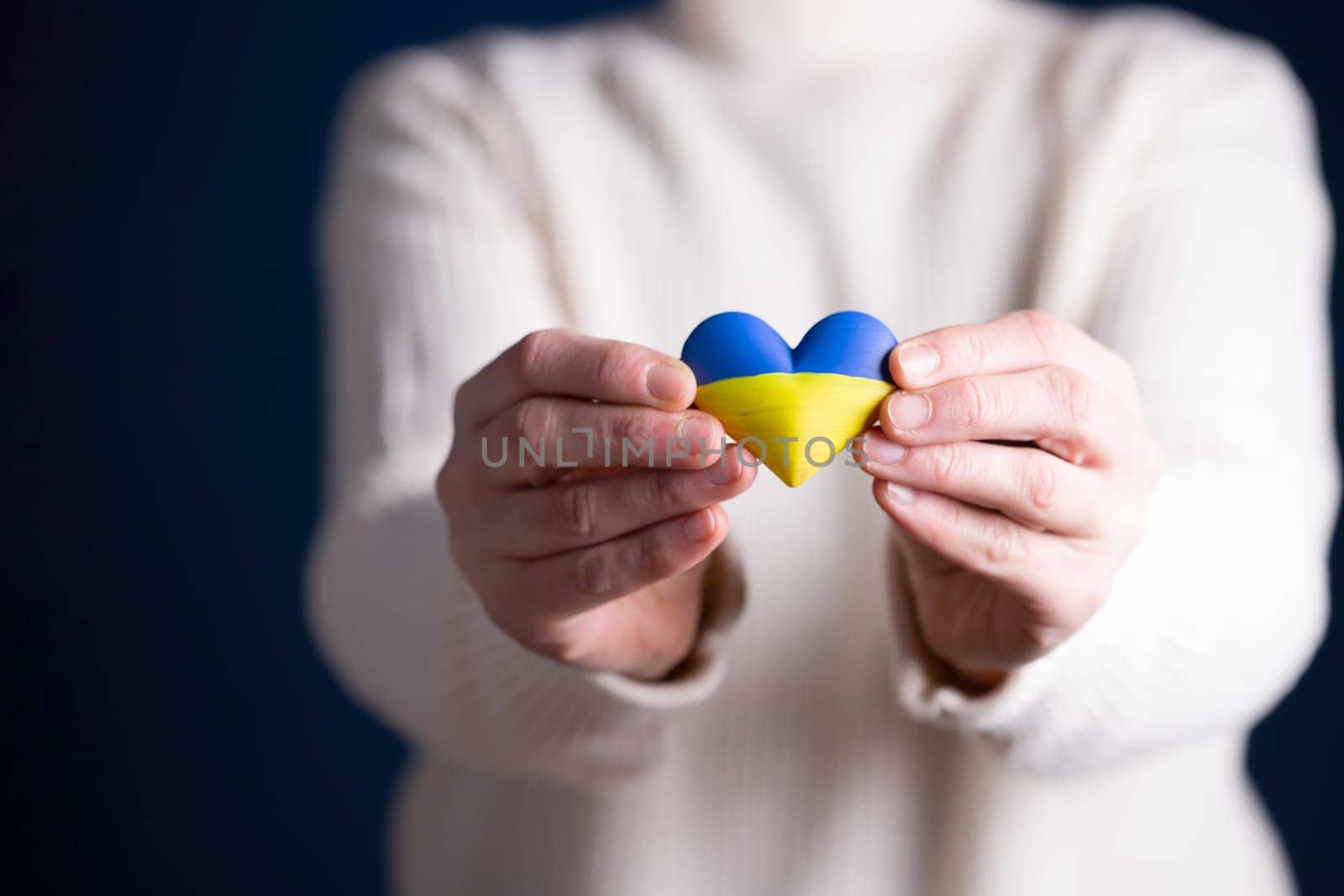 Heart shaped flag of Ukraine in female hands. The concept of solidarity with the citizens of Ukraine.