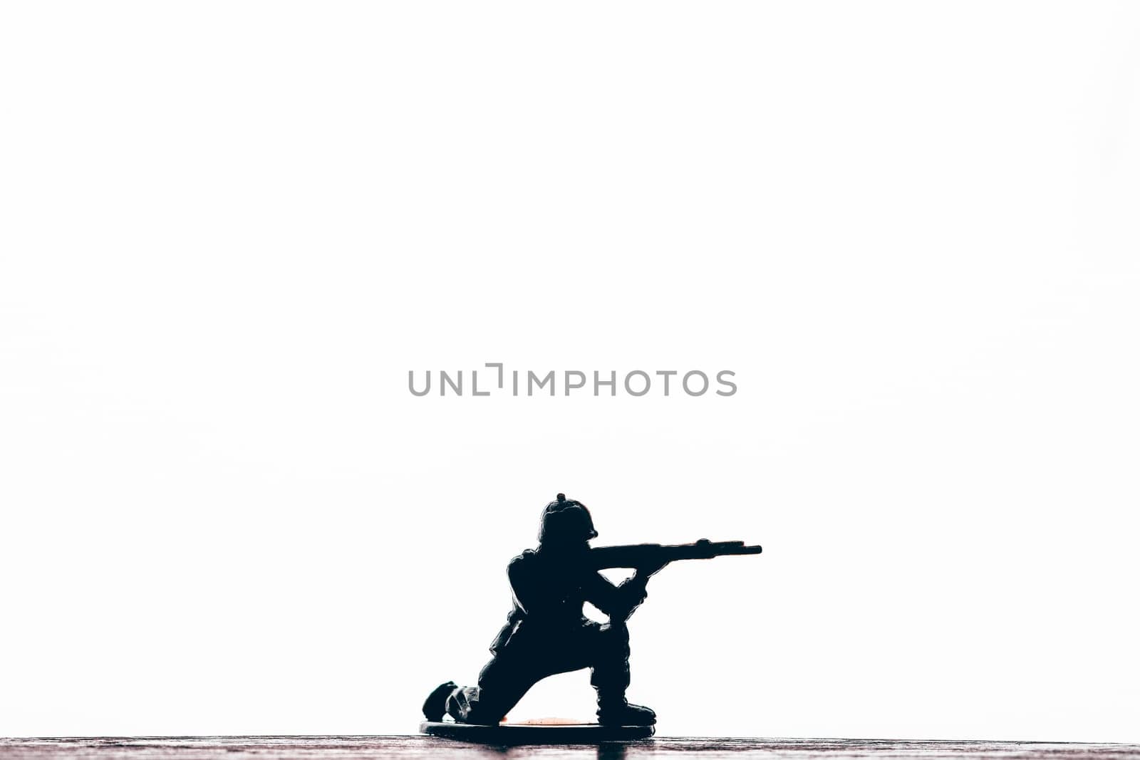 Silhouette of male soldier wearing army, uniform and helmet. Man holding weapon machine in hands. White studio background.
