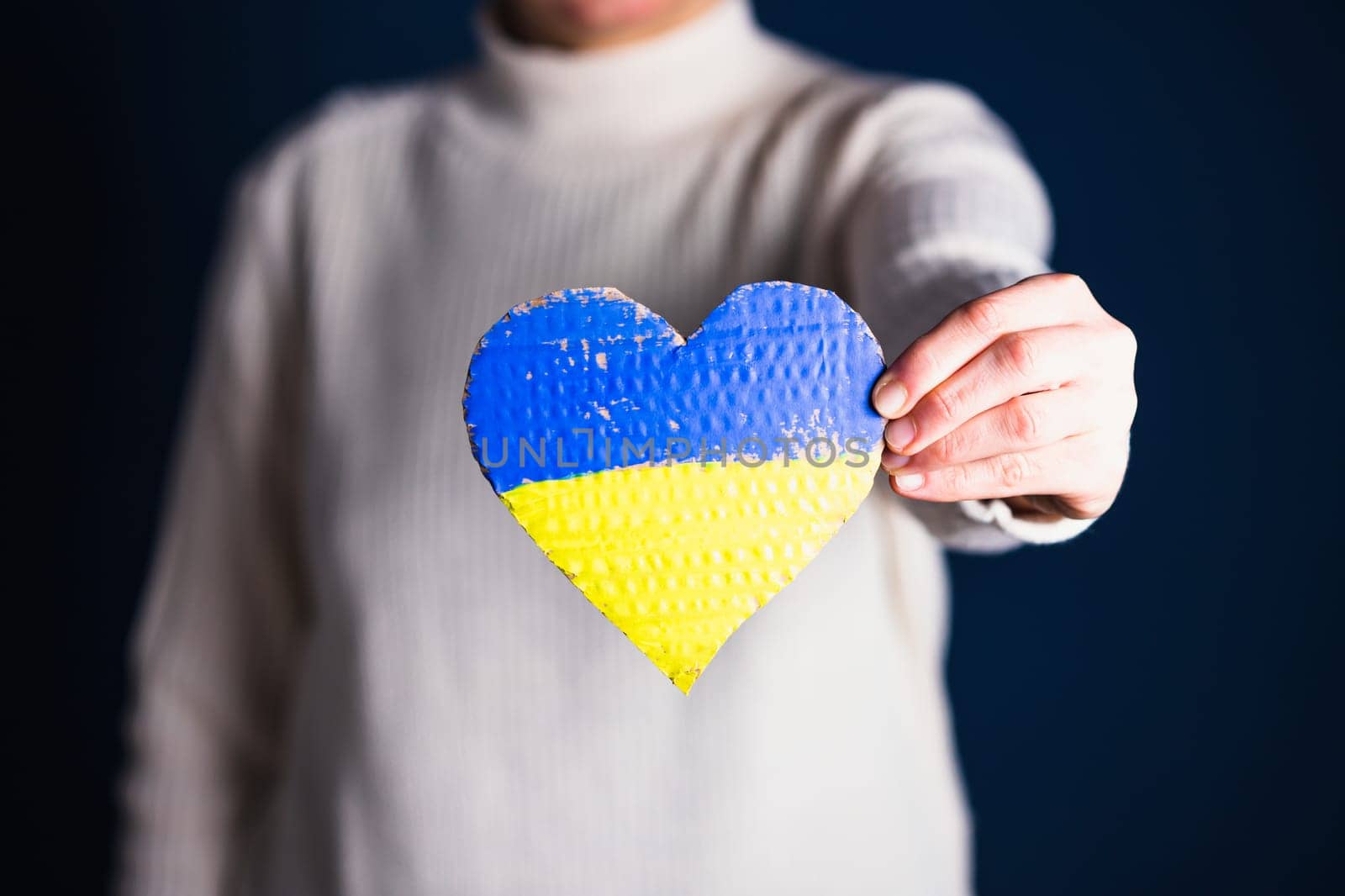 Heart shaped flag of Ukraine in female hands. The concept of solidarity with the citizens of Ukraine.