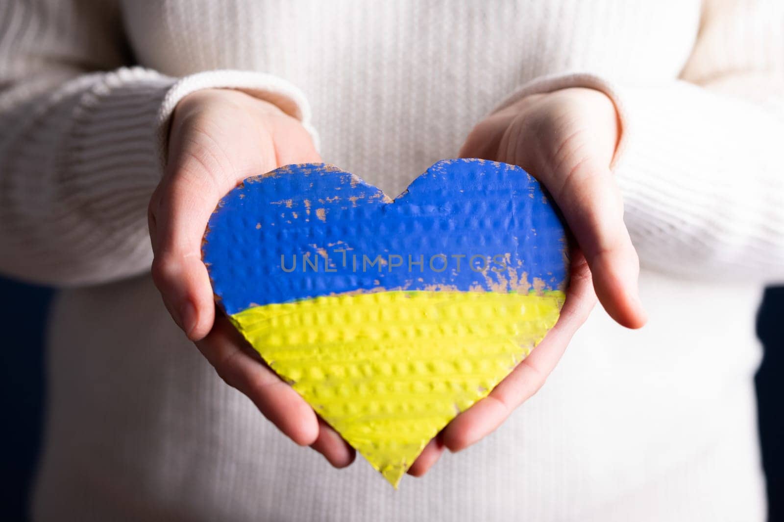 Heart shaped flag of Ukraine in female hands. The concept of solidarity with the citizens of Ukraine.
