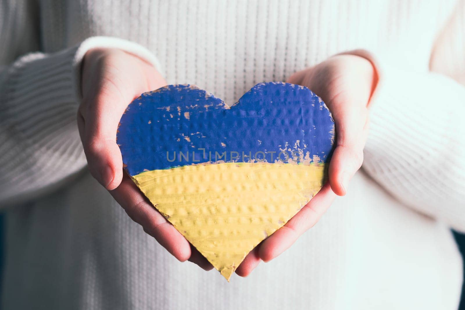 Heart shaped flag of Ukraine in female hands. The concept of solidarity with the citizens of Ukraine.