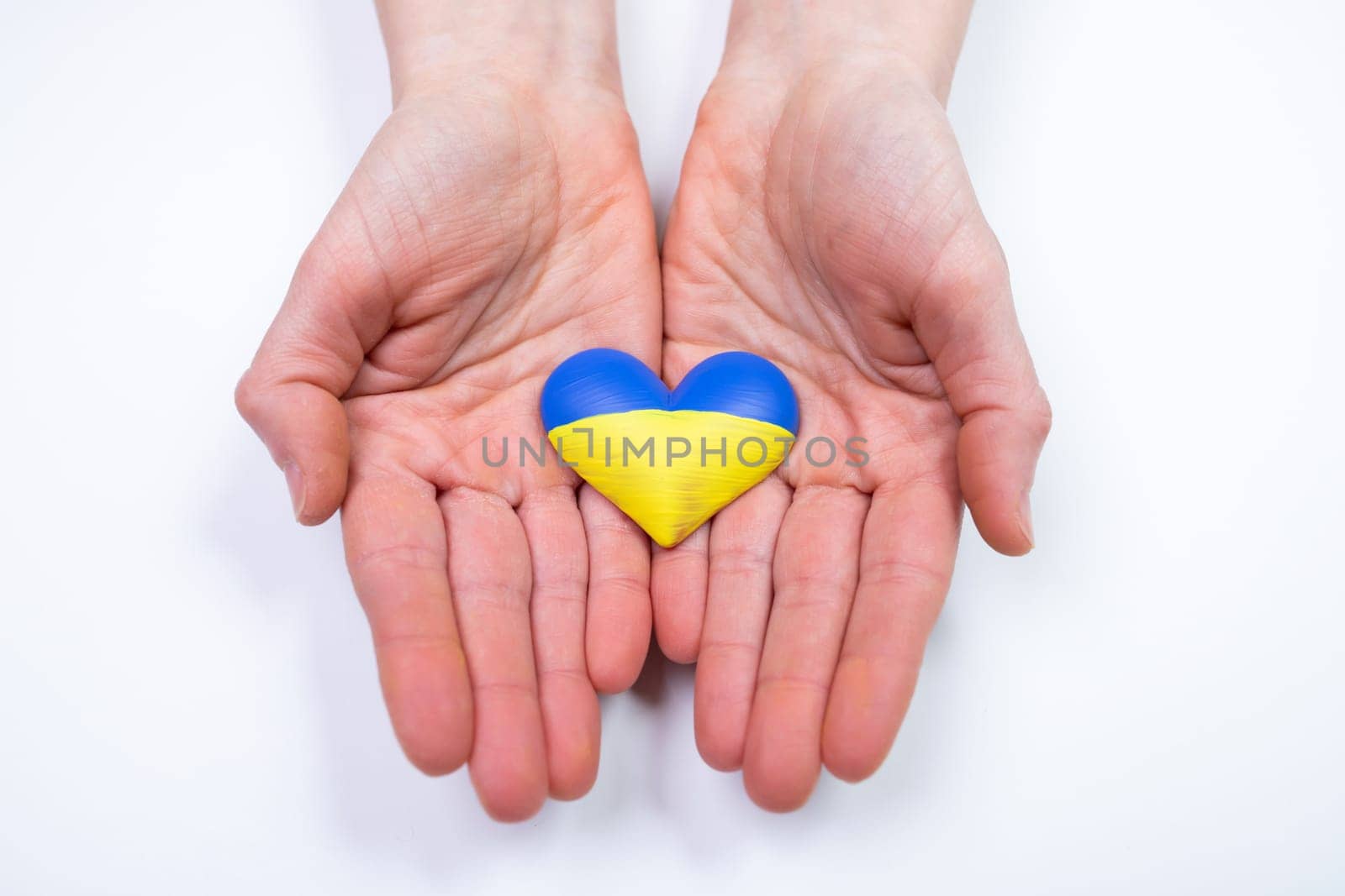 Heart shaped flag of Ukraine in female hands. The concept of solidarity with the citizens of Ukraine.