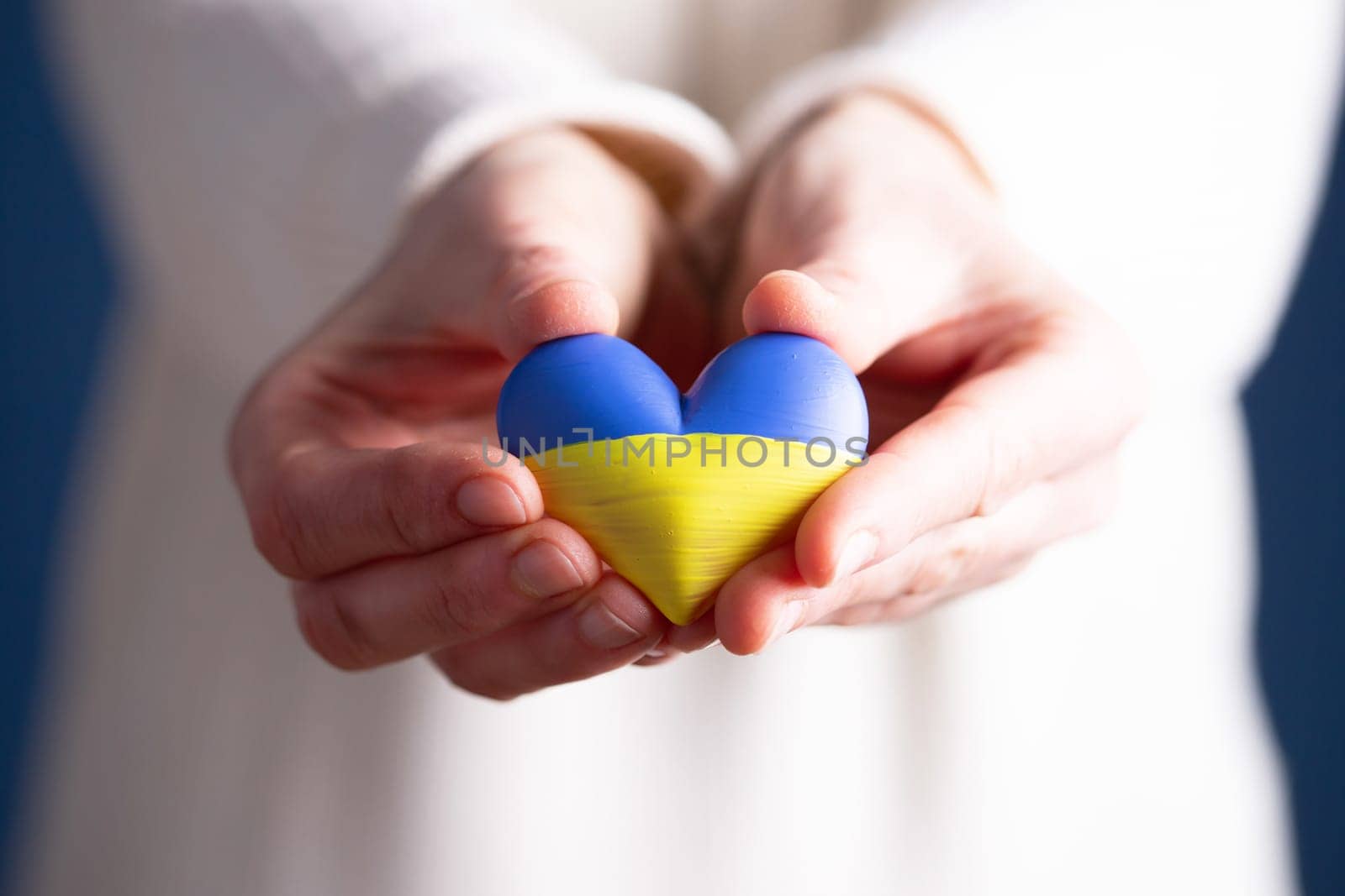 Heart shaped flag of Ukraine in female hands. The concept of solidarity with the citizens of Ukraine.