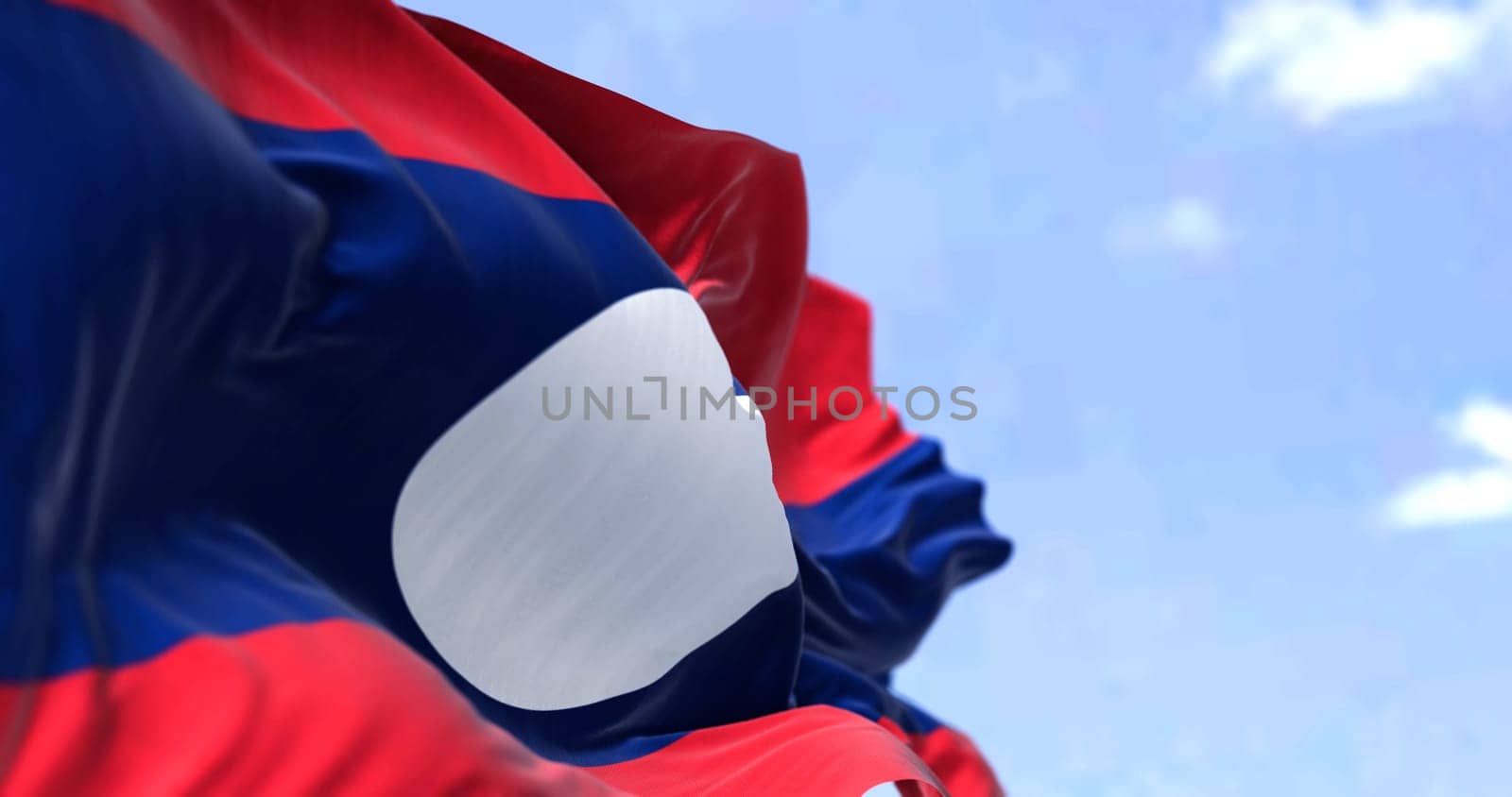 Detail of the national flag of Laos waving in the wind on a clear day. Laos is a socialist state and the only landlocked country in Southeast Asia. Selective focus.