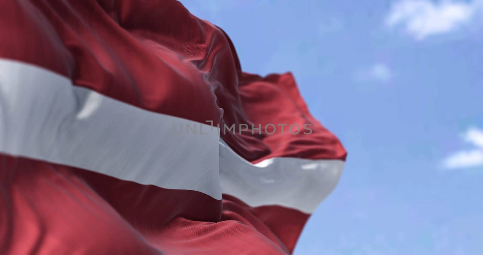Detail of the national flag of Latvia waving in the wind on a clear day. Latvia is a country in the Baltic region of Northern Europe. Selective focus.