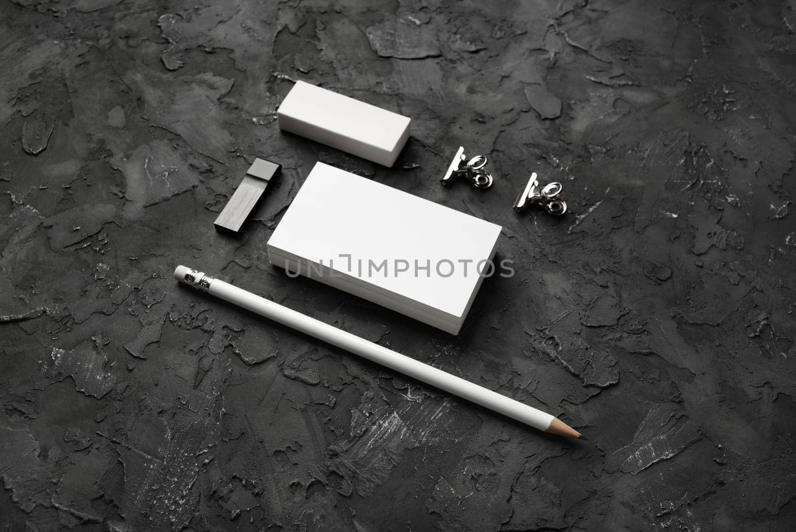 Blank stationery set on black plaster background. Blank business cards, pencil, eraser, usb flash drive and clips.
