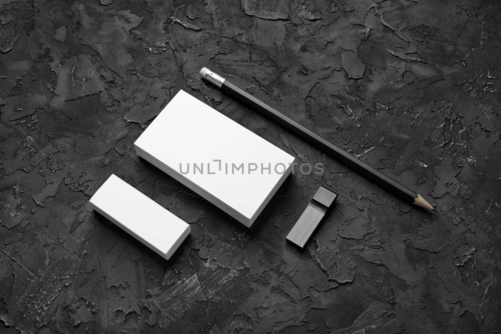 Photo of business cards, pencil, eraser and usb flash drive on black plaster background. Branding mock up.