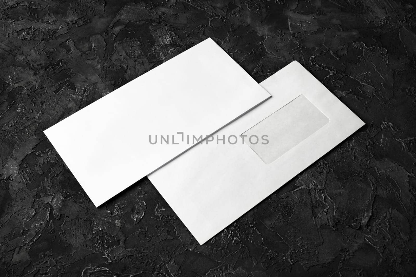 Two blank envelopes on black plaster background. Front and back side. Template for branding identity.