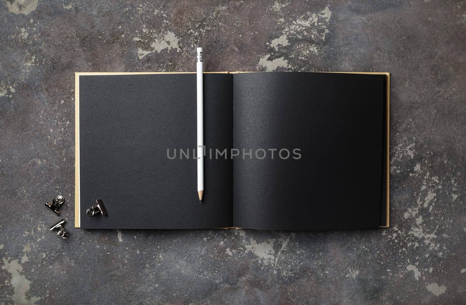 Blank black book and pencil on concrete background. Template for placing your design. Flat lay.